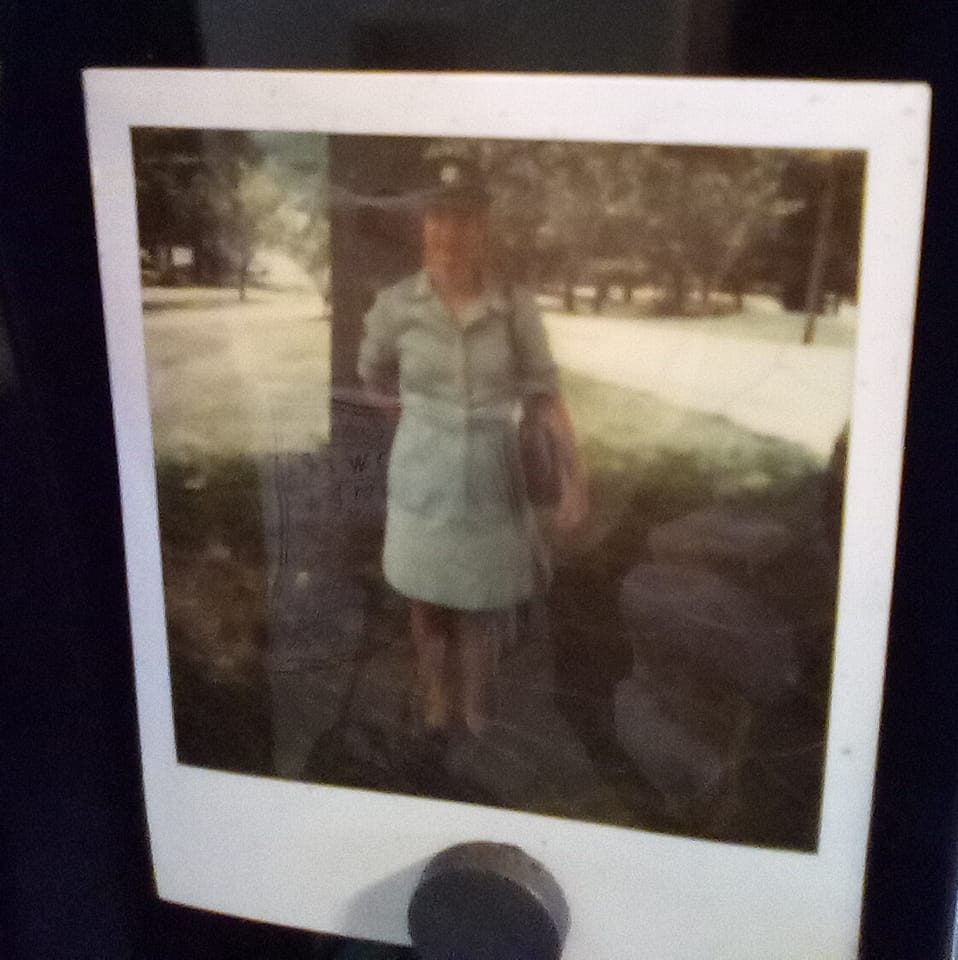 This is a photo of my Mother from back in the Vietnam War as a medic. Take a look at the reflections on the photo. You can see a stack of three heads, none of them are human. The bottom one is wearing a cement bag as a bandana and has his finger to his lips to tell me to shut up. On the right you can see some wet, white hands just got done mixing cement I'm sure. On the top it says "die boogie." I didnt'take this photo, it was just on my desktop today when I logged onto my computer. It looks like I've opened a can of worms I can't close. 